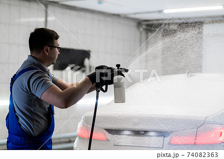 Worker covering automobile with foam at car wash. Worker covering automobile with foam at car wash. 74082363