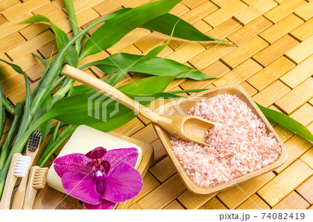 Spa, zen, massage concept. Pink himalayan bath salt with spoon, bamboo leaves, orchid, soap dish Spa, zen, massage concept. Pink himalayan bath salt with spoon, bamboo leaves, orchid, soap dish 74082419