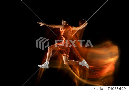 Young arabian basketball player of team in action, motion isolated on black background in mixed light. Concept of sport, movement, energy and dynamic. Young arabian basketball player of team in action, motion isolated on black background in mixed light. Concept of sport, movement, energy and dynamic. 74083609