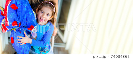 happy children easter egg background horizontal with copy space - little girl smiles embracing big 74084362