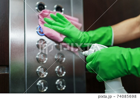 Disinfection and hygienic care using alcohol spray on the elevator button. 74085698