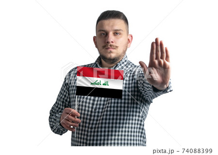 White guy holding a flag of Iraq and with a serious face shows a hand stop sign isolated on a white background 74088399