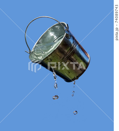 A falling buckets splashes water, on a background of blue sky. A falling buckets splashes water, on a background of blue sky. 74089743