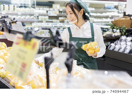 スーパーで品出しをするマウスシールドをした女性従業員 74094467