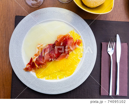 Delicious serving of pineapple and melon carpaccio with thinly sliced prosciutto 74095102