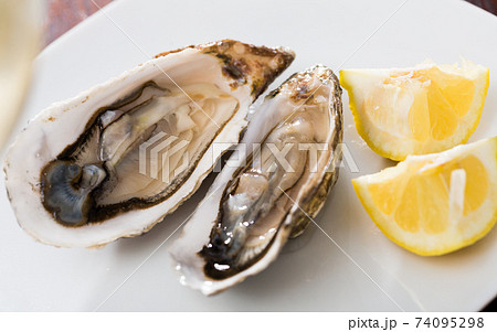 Tasty oysters with lemon on plate top view Tasty oysters with lemon on plate top view 74095298