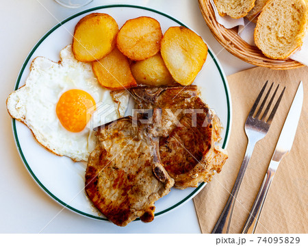 Pork chop with potatoes and scrambled eggs Pork chop with potatoes and scrambled eggs 74095829