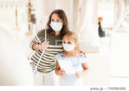 Mom and her daughter in protective masks on tour of the museum 74096486
