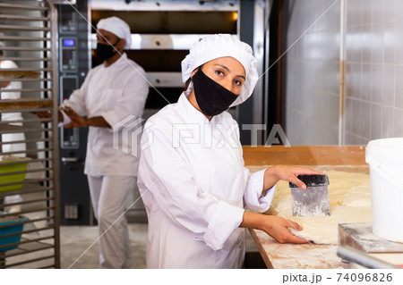 Female baker portioning dough and weighing pieces Female baker portioning dough and weighing pieces 74096826