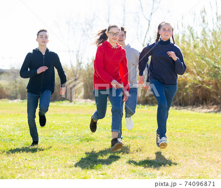 Group of joyful teenagers running down in the park 74096871