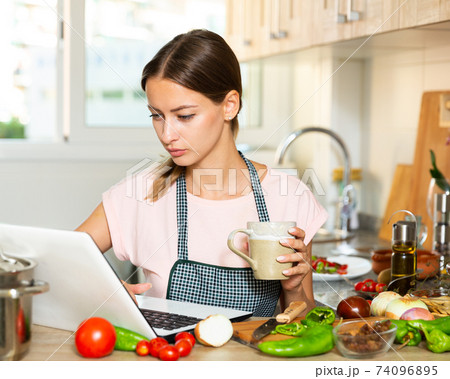 Housewife drinking coffee and using laptop 74096895