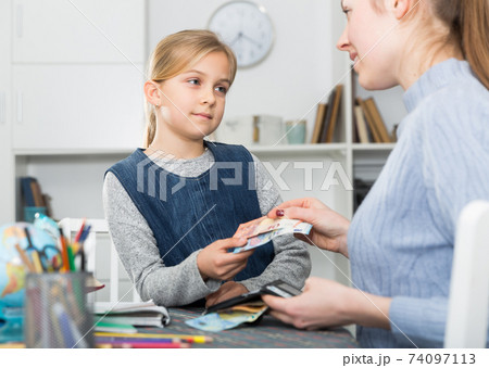 Mother hands over money to little daughter Mother hands over money to little daughter 74097113