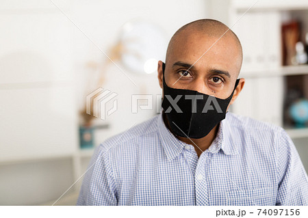 Portrait of positive business man in protective mask with folder of documents Portrait of positive business man in protective mask with folder of documents 74097156