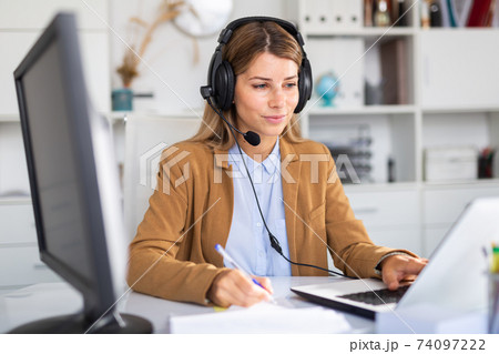 positive woman working with headphones on her laptop in white room positive woman working with headphones on her laptop in white room 74097222