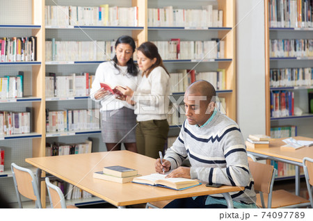 Young adult man studying in public library Young adult man studying in public library 74097789