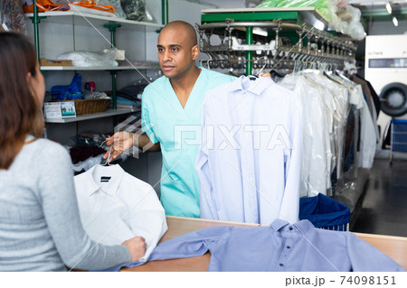 Man dry-cleaning worker giving clothes to customer Man dry-cleaning worker giving clothes to customer 74098151