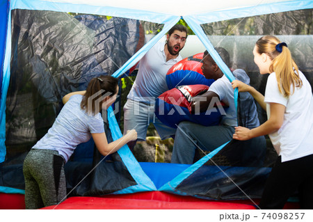 Hispanic guy on inflatable boxing ring with African friend Hispanic guy on inflatable boxing ring with African friend 74098257