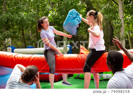 Females wrestling by pillows on inflatable log Females wrestling by pillows on inflatable log 74098258