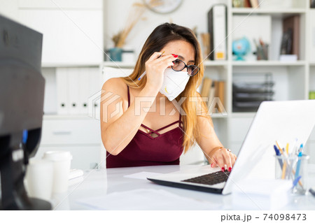 Young colombian woman in mask working with laptop 74098473