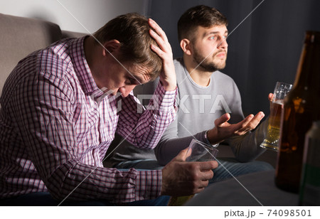 Upset male friends watching tv Upset male friends watching tv 74098501