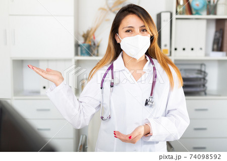 Female doctor in medical mask inviting to doctor's office Female doctor in medical mask inviting to doctor's office 74098592