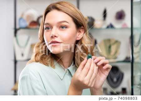 Woman trying on emerald earrings Woman trying on emerald earrings 74098803