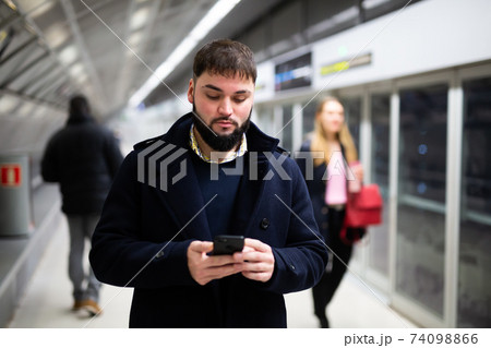 Young man with phone on subway platform Young man with phone on subway platform 74098866