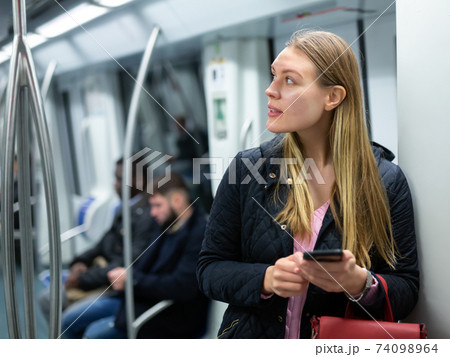 Young woman with phone in subway car Young woman with phone in subway car 74098964