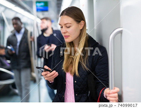 Young woman browsing on phone in metro car 74099017