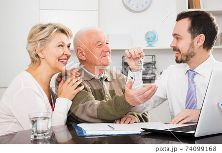 Old man and woman sign sale agreement Old man and woman sign sale agreement 74099168