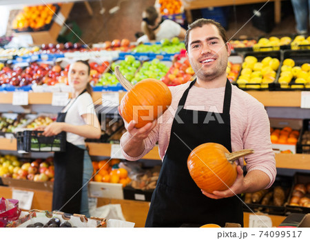 Seller with pumpkin in supermarket 74099517