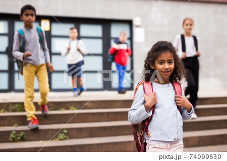 Curly mulatto tween girl walking to school campus after lessons Curly mulatto tween girl walking to school campus after lessons 74099630