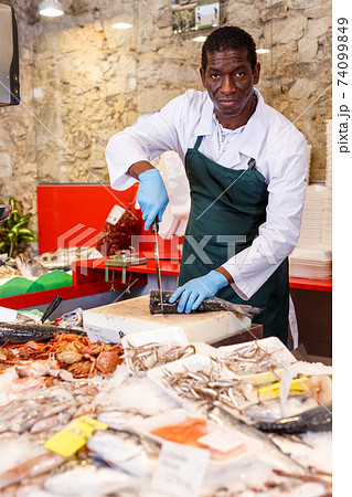 Salesman preparing fish for sale Salesman preparing fish for sale 74099849