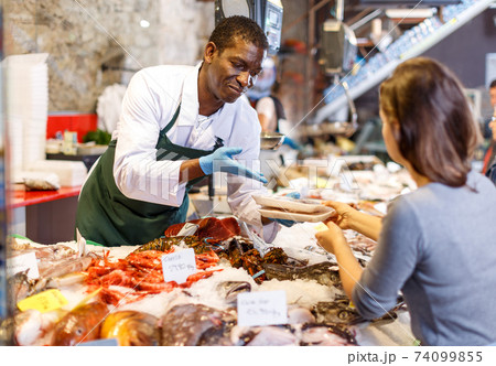 Salesman serving customer raw fish Salesman serving customer raw fish 74099855