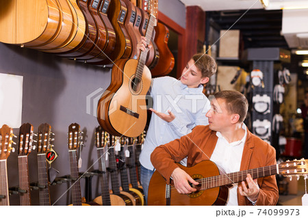 Boy and father choosing acoustic guitar 74099973