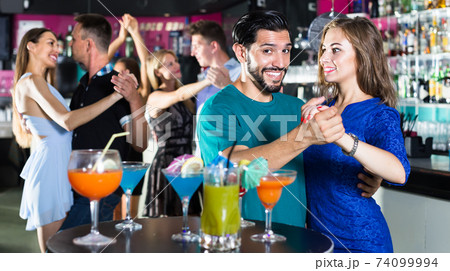 Young positive women with men are dancing in pairs in the nightclub 74099994