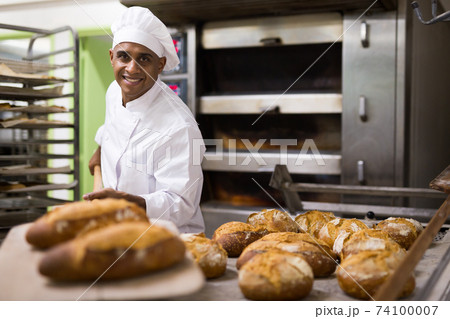 Man holding bread on peel in bakery Man holding bread on peel in bakery 74100007