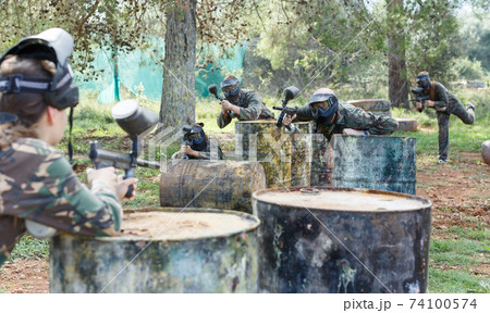 Two opposing teams in camouflage playing paintball against each other 74100574