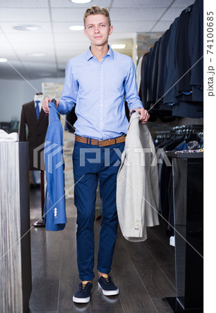 Consumer man holding on hanger colored jackets 74100685