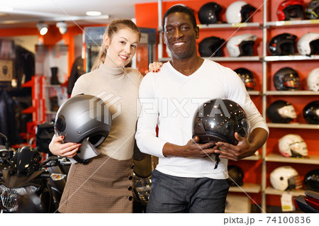 Smiling female and male customers satisfied with purchases in motorcycle shop 74100836