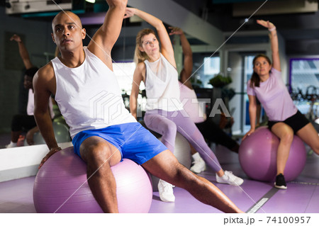 People working out with aerobic ball in modern gym People working out with aerobic ball in modern gym 74100957