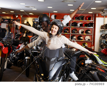 Couple sitting together on new motorcycle in store and having fun 74100969