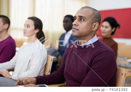 Multiethnic group of adult people studying together at tables . Focus on Latin American man Multiethnic group of adult people studying together at tables . Focus on Latin American man 74101392