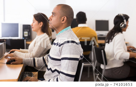 Focused hispanic male student working on computer in library 74101653