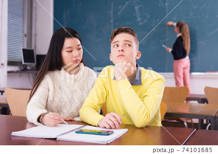Chinese girl student explaining learning material to bored classmate 74101685