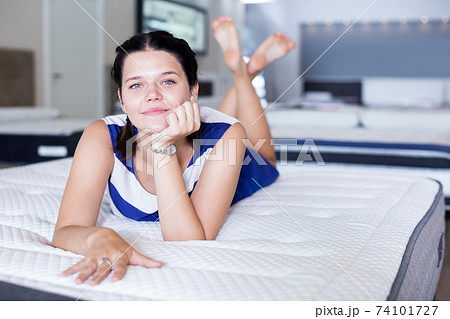 Female lying on soft mattress and smiling in store 74101727