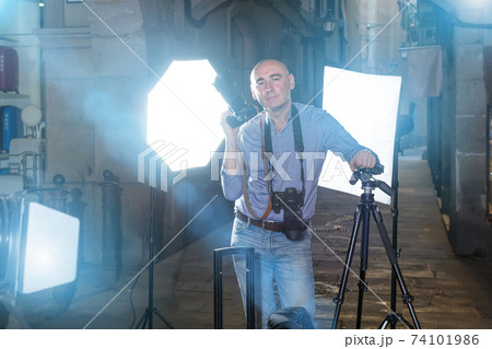 Portrait of adult photographer with his camera during photo shoo Portrait of adult photographer with his camera during photo shoo 74101986