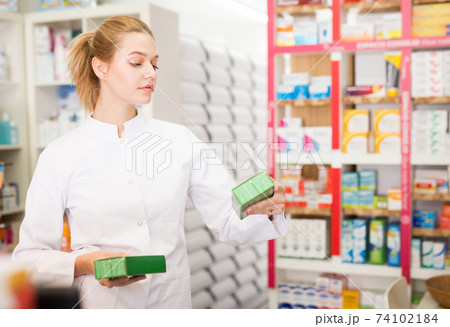 Young friendly female pharmacist suggesting useful tablets in pharmacy 74102184