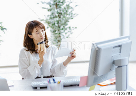 紙資料を見て首を傾げるデスクワーク中の女性 74105791