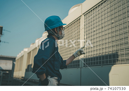 ビル屋上の空調設備を点検する業者 ビル屋上の空調設備を点検する業者 74107530